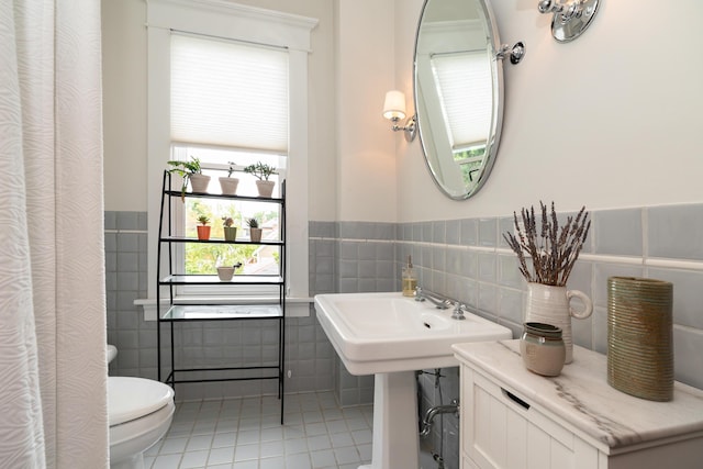 bathroom with tile patterned floors, toilet, and tile walls