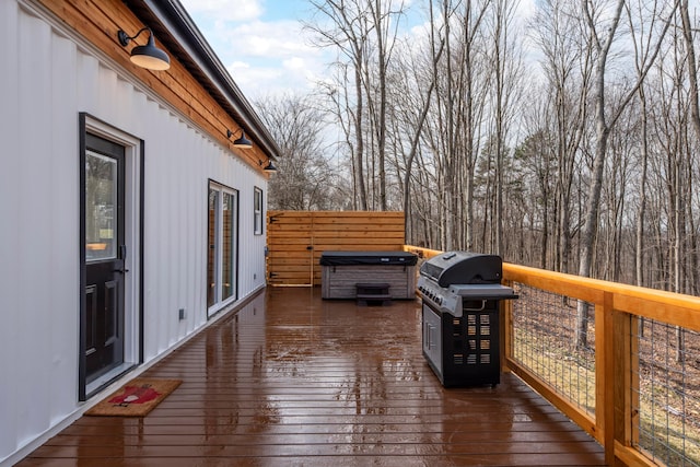 wooden deck featuring a hot tub and a grill