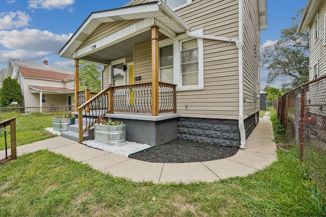 doorway to property featuring a lawn and covered porch