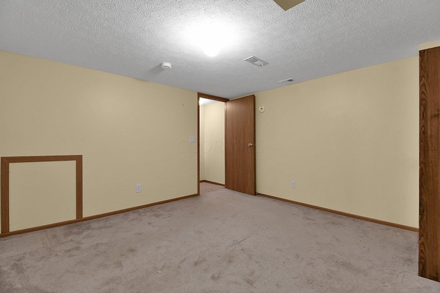 unfurnished room featuring a textured ceiling and light colored carpet