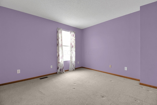 carpeted empty room featuring a textured ceiling