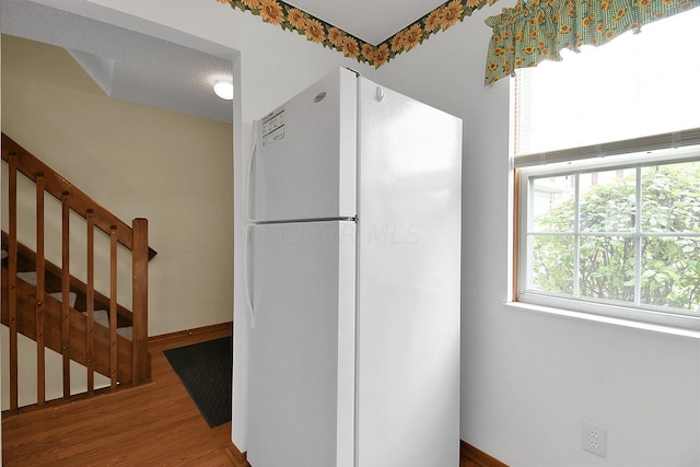 kitchen featuring hardwood / wood-style floors, white fridge, and a textured ceiling