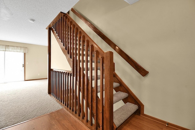 staircase with hardwood / wood-style floors and a textured ceiling