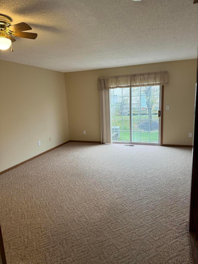 carpeted empty room with ceiling fan and a textured ceiling