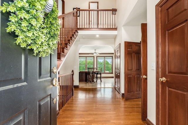 foyer entrance with a towering ceiling, light hardwood / wood-style floors, and ceiling fan