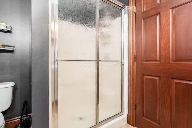 bathroom with toilet and a shower with shower door