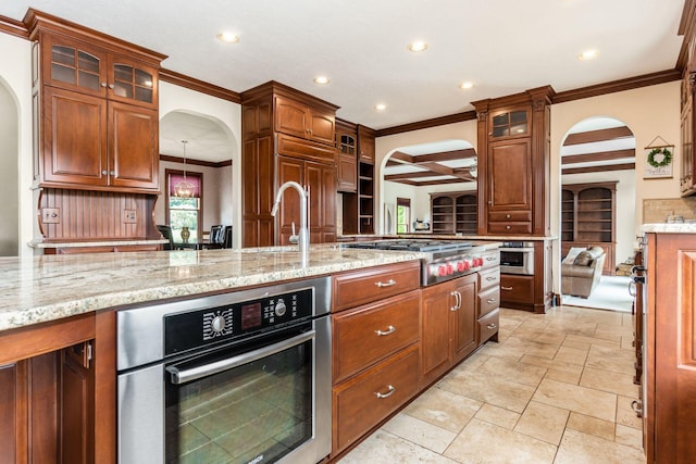 kitchen with beam ceiling, light stone counters, ornamental molding, and appliances with stainless steel finishes