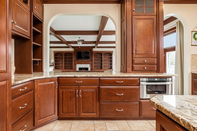 kitchen with beamed ceiling, stainless steel oven, light stone countertops, and coffered ceiling