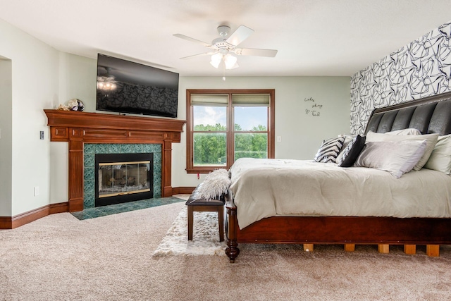 carpeted bedroom with a tile fireplace and ceiling fan