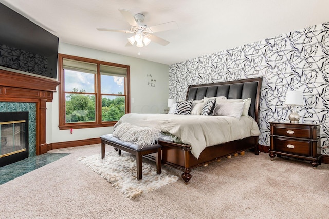 carpeted bedroom featuring ceiling fan and a fireplace