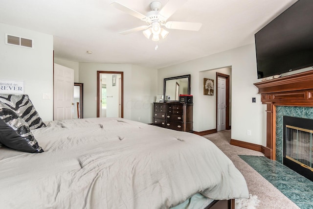 carpeted bedroom with a tiled fireplace and ceiling fan