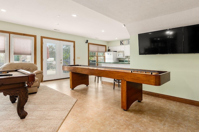 recreation room featuring french doors, light tile patterned flooring, and a textured ceiling