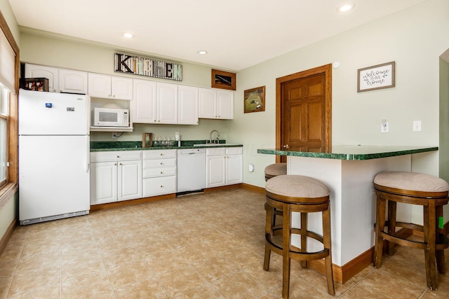 kitchen with a kitchen breakfast bar, white cabinets, and white appliances