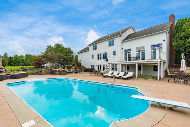 view of pool with an outdoor living space, a patio, and a diving board