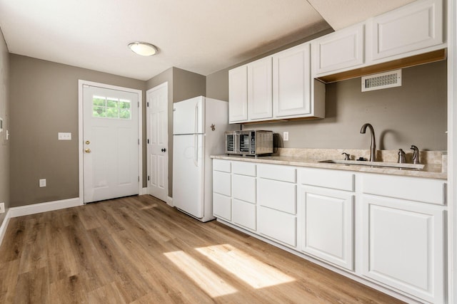 kitchen with sink, white cabinets, light wood-type flooring, and white refrigerator