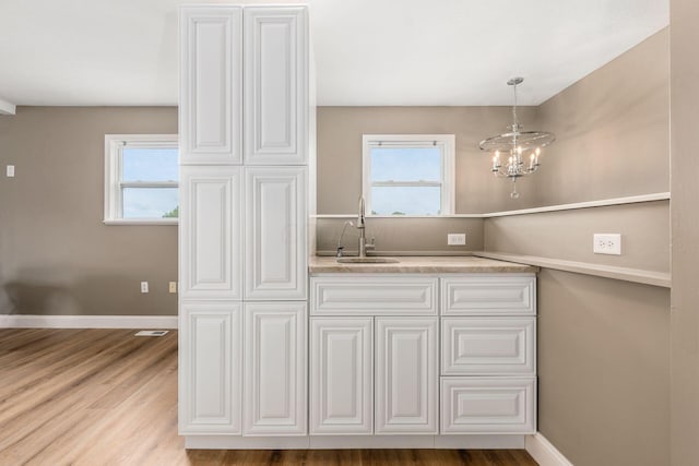 kitchen featuring pendant lighting, light hardwood / wood-style floors, a wealth of natural light, and sink