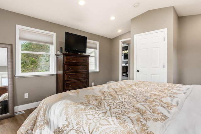 bedroom with hardwood / wood-style floors, lofted ceiling, and multiple windows