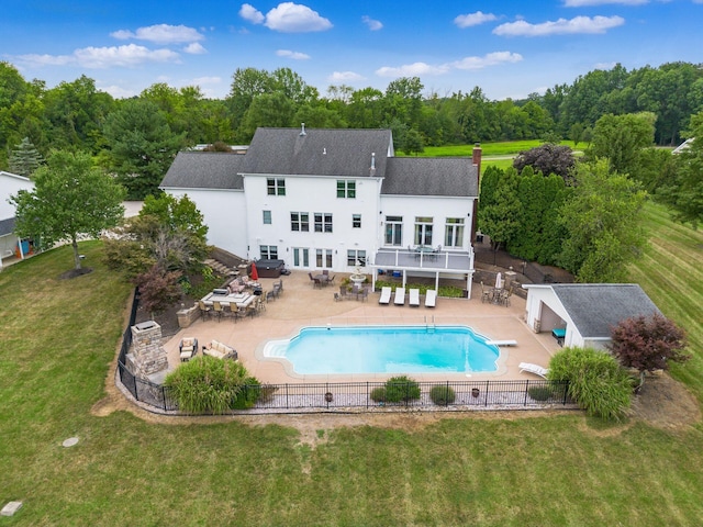 rear view of property with a lawn, a patio area, an outdoor hangout area, and a fenced in pool