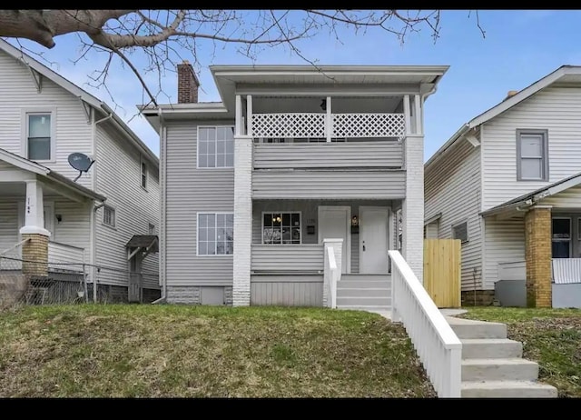 view of front of house featuring a balcony and a front lawn