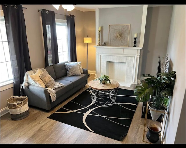 living room with wood-type flooring and a tiled fireplace