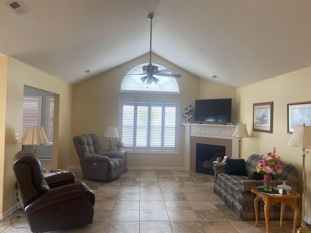 living room featuring a tile fireplace, light tile patterned floors, vaulted ceiling, and ceiling fan