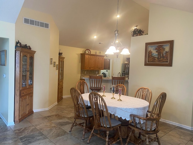 dining room with a chandelier, washer / clothes dryer, and high vaulted ceiling