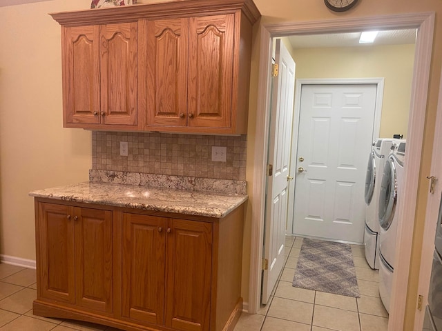 kitchen featuring washer and dryer, light tile patterned flooring, light stone countertops, and tasteful backsplash