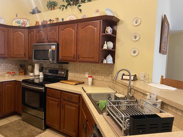 kitchen featuring kitchen peninsula, light tile patterned floors, stainless steel appliances, and tasteful backsplash