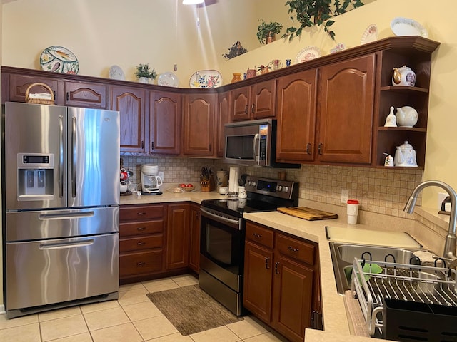 kitchen featuring sink, vaulted ceiling, decorative backsplash, light tile patterned floors, and appliances with stainless steel finishes