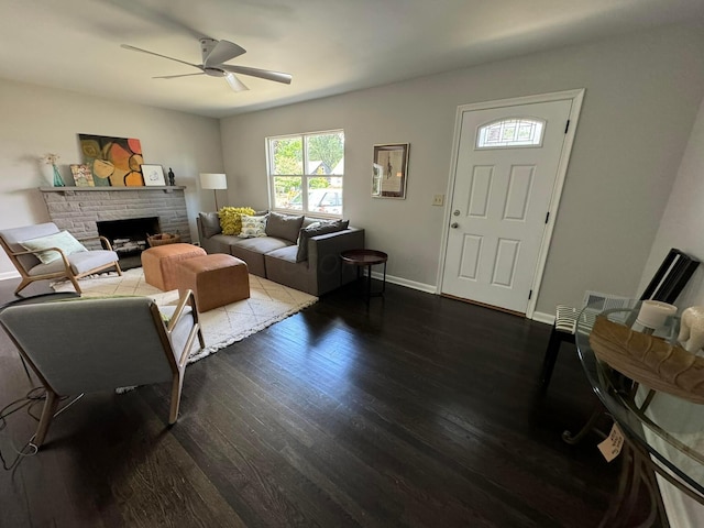 living room with a stone fireplace, ceiling fan, and dark hardwood / wood-style floors