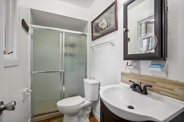 bathroom featuring tasteful backsplash, toilet, a shower with shower door, and sink