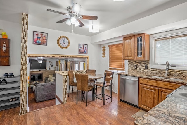 kitchen featuring dishwasher, light hardwood / wood-style floors, dark stone countertops, and sink