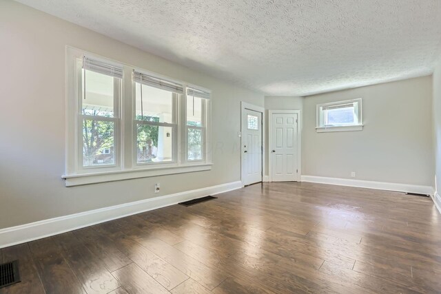 spare room featuring a textured ceiling and dark hardwood / wood-style flooring