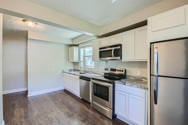 75 N Huron Ave, Columbus, OH 43204 - kitchen featuring appliances with stainless steel finishes, white cabinetry, light stone countertops, dark wood-style floors, and a textured ceiling