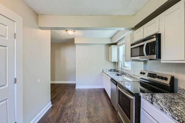 75 N Huron Ave, Columbus, OH 43204 - kitchen with stainless steel appliances, a textured ceiling, dark wood-type flooring, white cabinetry, and light stone counters