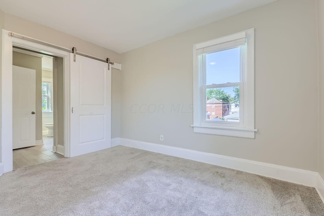 75 N Huron Ave, Columbus, OH 43204 - unfurnished bedroom with carpet floors, a barn door, and connected bathroom