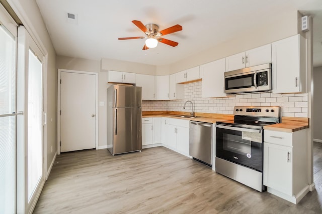 kitchen with wooden counters, sink, appliances with stainless steel finishes, light hardwood / wood-style floors, and white cabinetry