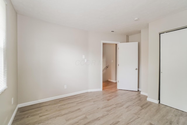 unfurnished bedroom featuring light wood-type flooring and a closet