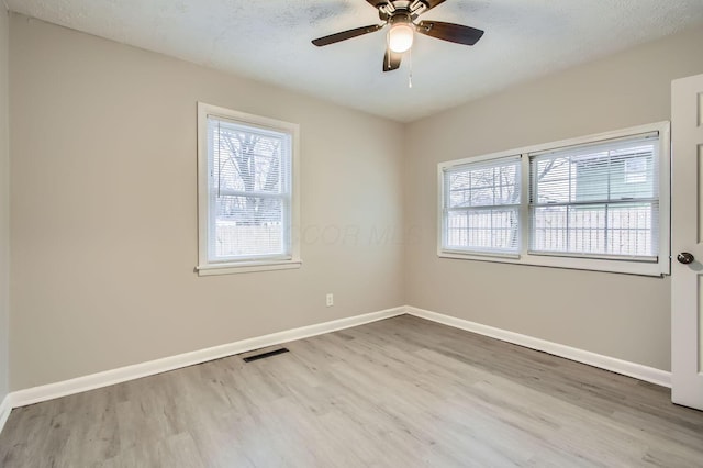 empty room with ceiling fan, a textured ceiling, and light hardwood / wood-style flooring