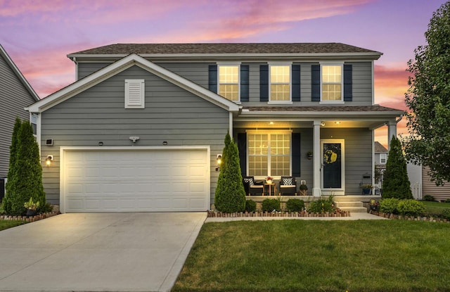 view of front of home with a yard, a porch, and a garage