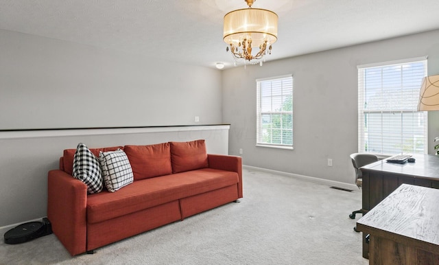 carpeted office space featuring a healthy amount of sunlight, a textured ceiling, and an inviting chandelier