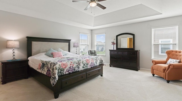 bedroom featuring a raised ceiling, ceiling fan, and light carpet