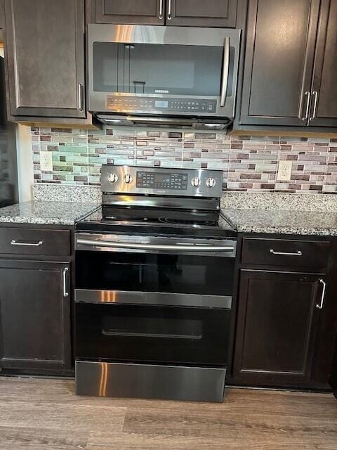 kitchen featuring light stone countertops, decorative backsplash, dark brown cabinetry, stainless steel appliances, and light hardwood / wood-style flooring