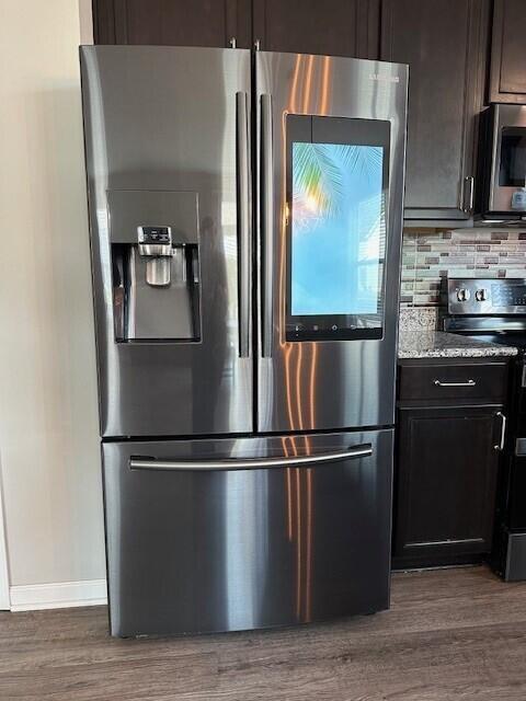 kitchen with dark hardwood / wood-style floors, light stone countertops, tasteful backsplash, dark brown cabinets, and stainless steel appliances