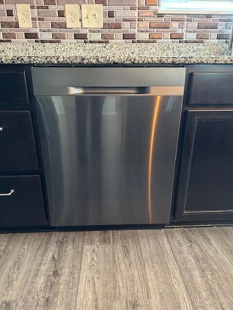 room details featuring decorative backsplash, hardwood / wood-style floors, stainless steel dishwasher, and light stone counters