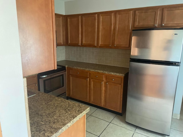 kitchen with light tile patterned floors, backsplash, and appliances with stainless steel finishes