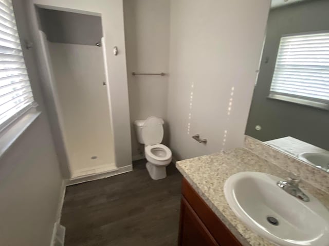 bathroom featuring hardwood / wood-style flooring, vanity, toilet, and walk in shower