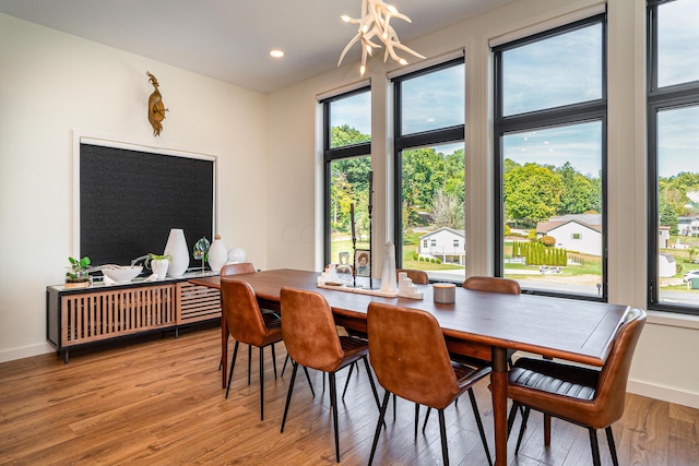 dining room featuring a healthy amount of sunlight, light wood-type flooring, and a chandelier