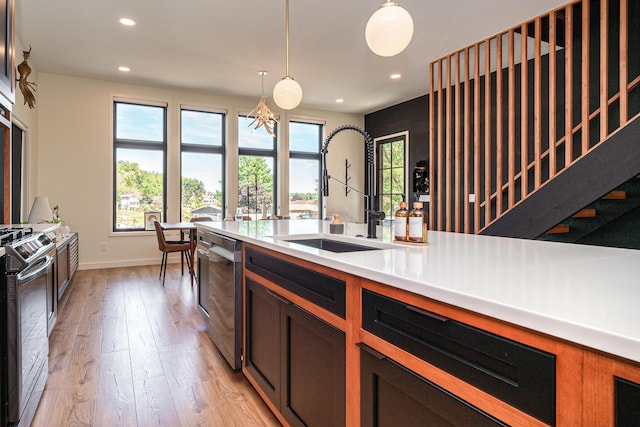 kitchen featuring stainless steel appliances, sink, light hardwood / wood-style flooring, a chandelier, and hanging light fixtures