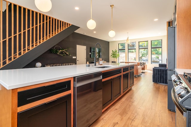 kitchen featuring stainless steel appliances, sink, hanging light fixtures, and light wood-type flooring